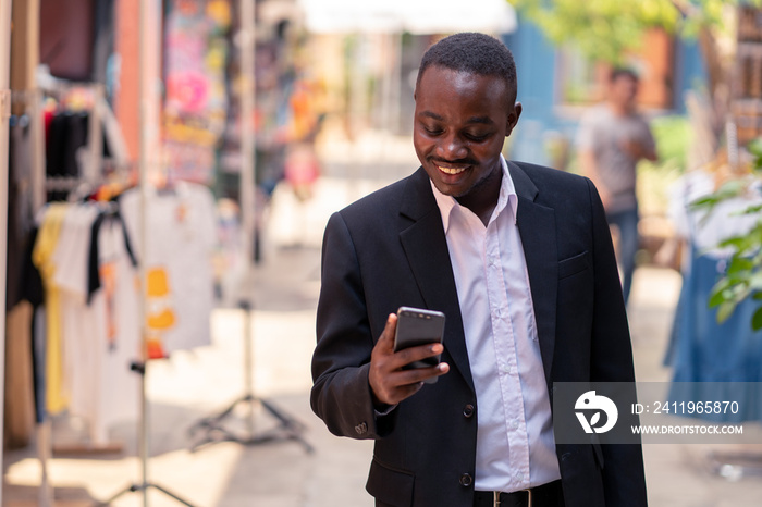 African business man using his phone and walking in the city