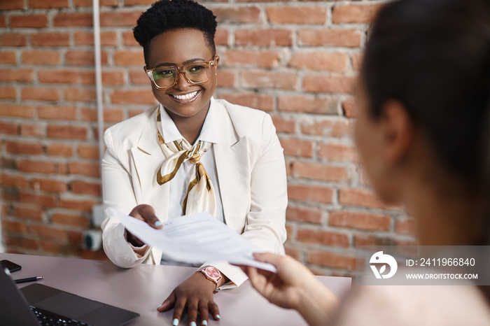 Black female human resource manager takes CV from a candidate during job interview in the office.