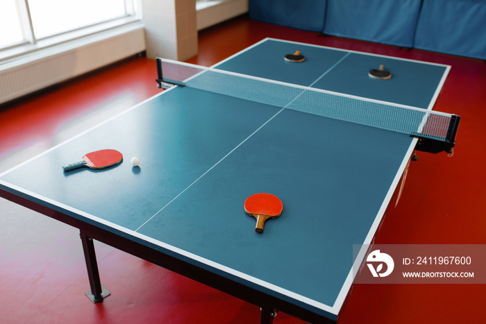 Ping pong rackets on game table with net, nobody