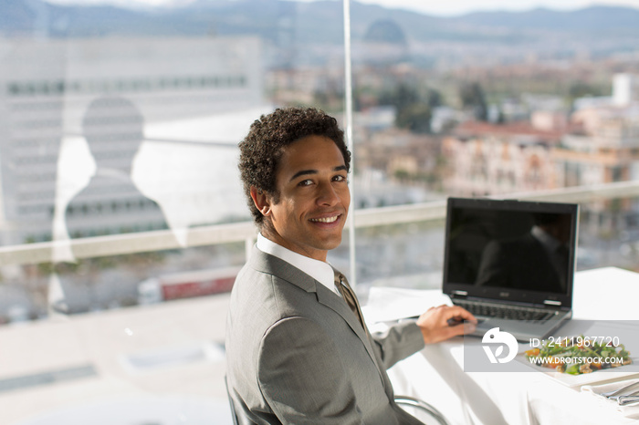 Portrait confident businessman eating lunch at laptop in office