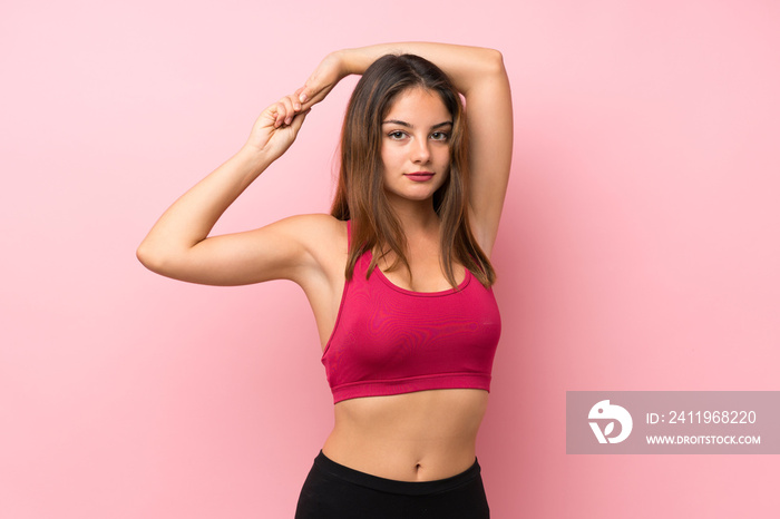 Young sport girl over isolated pink background stretching