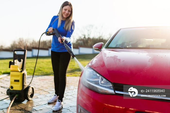 Young woman washing her carr using high pressure water. Selective focus.