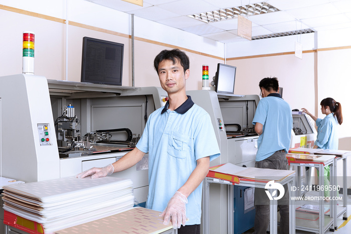 Colleagues using manufacturing machines to make flexible circuits, looking at camera