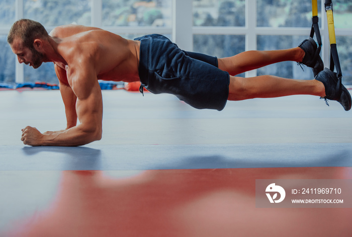 Plank it. Confident muscled young man wearing sport wear and doing plank position while exercising i