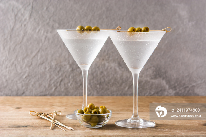 Classic Dry Martini with olives in glass on wooden table