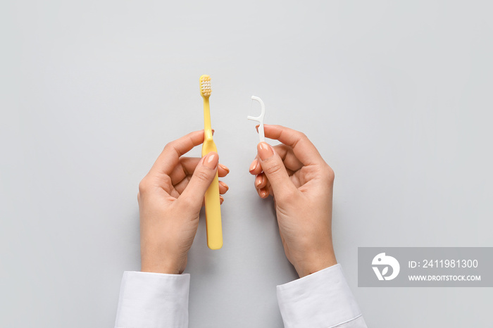 Woman with toothpick and brush on light background