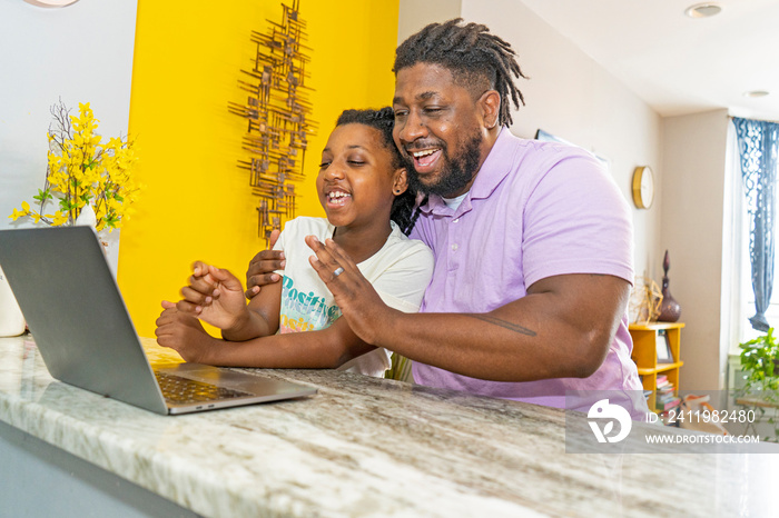 Father and daughter Êusing laptop at home