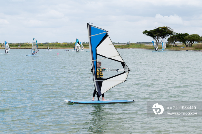 young teenager woman windsurfing on the lake of the island of re windsurf board