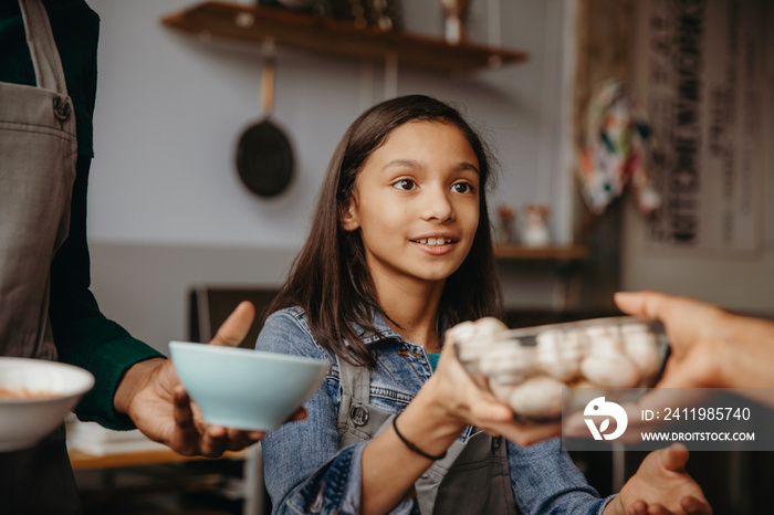 Smiling girl giving bowl of mushrooms to woman in cooking class