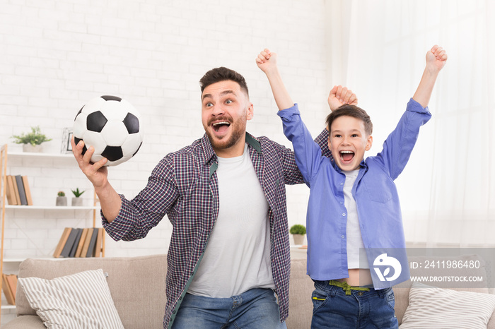 情绪激动的父子用足球欢呼，在家庆祝进球