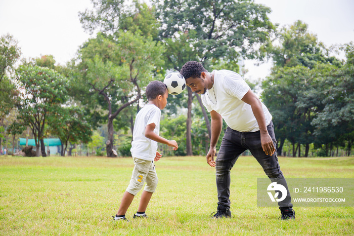 Cheerful african american father and son playing with football in park, Happiness family concepts