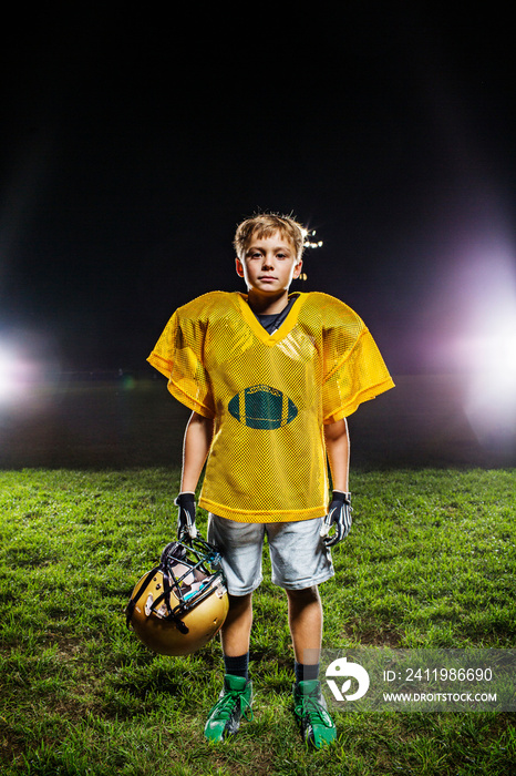 Portrait of boy with helmet standing in field at night