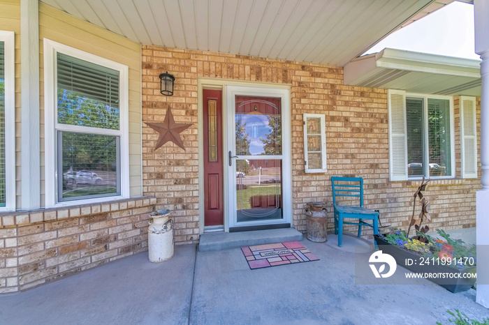 Home entrance with glass storm door over the burgundy door with side panel