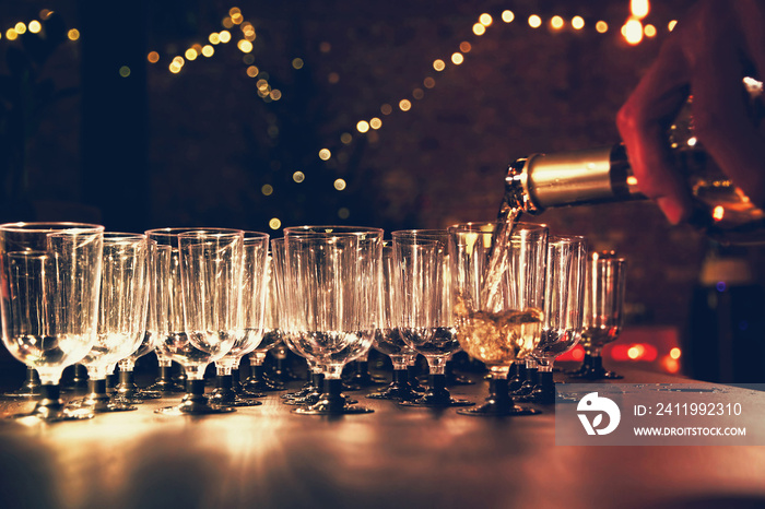 Man pouring wine in the glass on holiday table in night-time lighting.