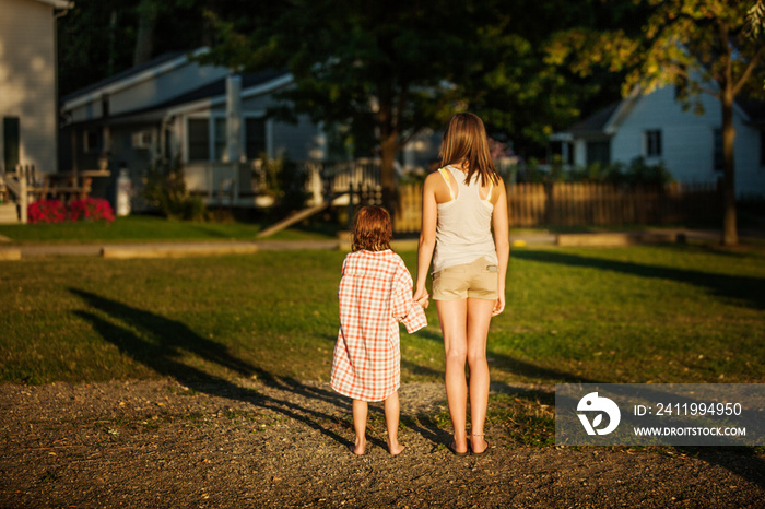 Rear view of siblings looking at house