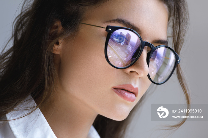 Close up portrait of Young woman with a reflection of modern city inside eyeglasses