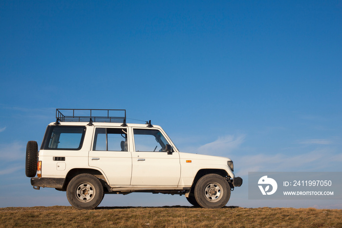 White jeep parked on a high hill off-road.