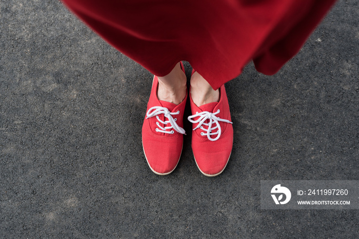 穿着红色运动鞋的女性脚踩在人行道上。俯视图
