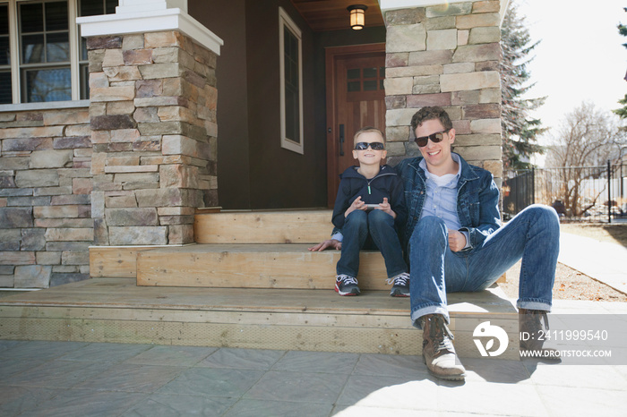 dad and son sitting on front stairs of residence