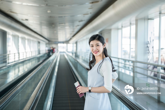 年轻商务女士在机场乘坐移动电梯