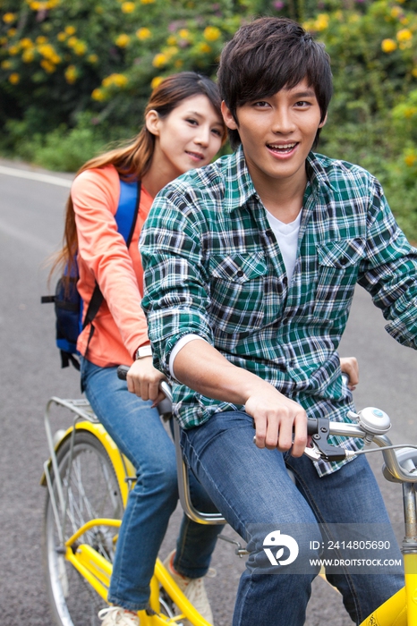 年轻大学生情侣在校园里骑车