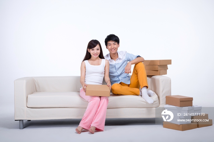 棚拍年轻情侣坐在沙发上抱着快递盒