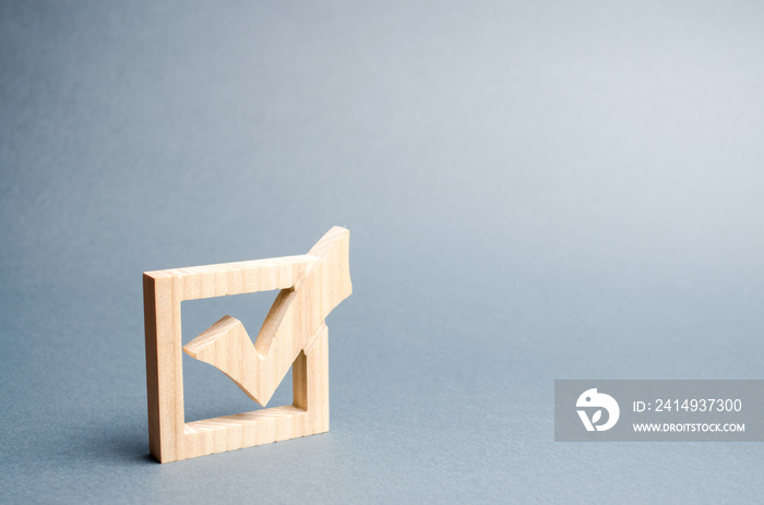 wooden checkmark for voting on elections on a gray background. Presidency or parliamentary elections, a referendum. Survey of the population, statistics, task. Democracy and freedom. Selective focus