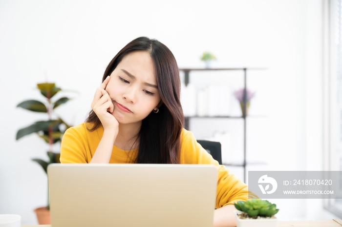 一名亚洲年轻女子在家里认真地使用笔记本电脑。她在思考解决问题的方法