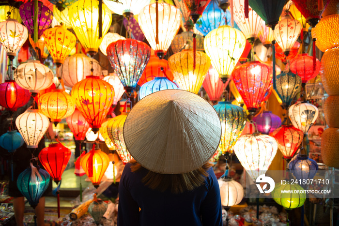 Tourist woman is wearing Non La (Vietnamese tradition hat) and looking colorful lanterns spread ligh