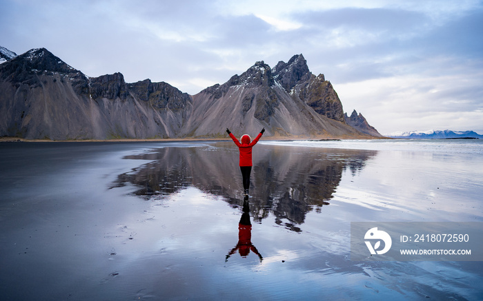 勇敢女孩的冰岛风景照，她骄傲地举起双臂站在维斯特拉霍恩面前