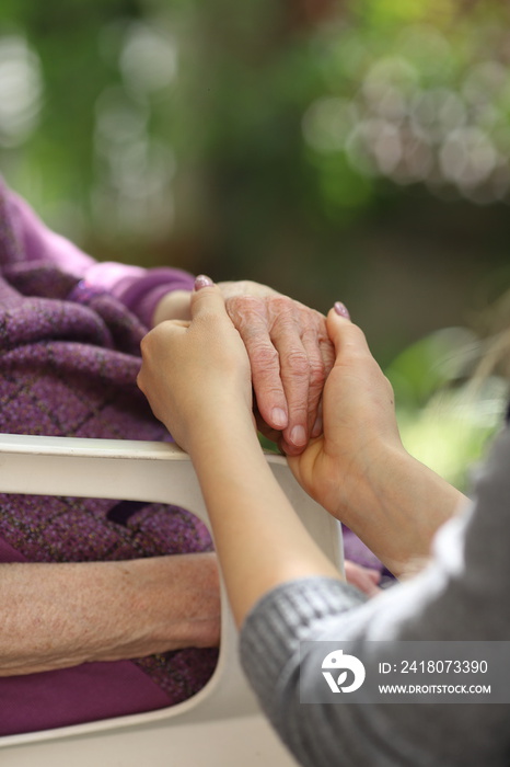 年轻的看护人牵着老年人的手。老年人的概念