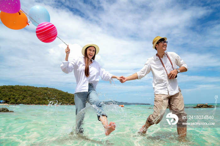 Asian couple run and happy on Pattaya beach with balloon on hand