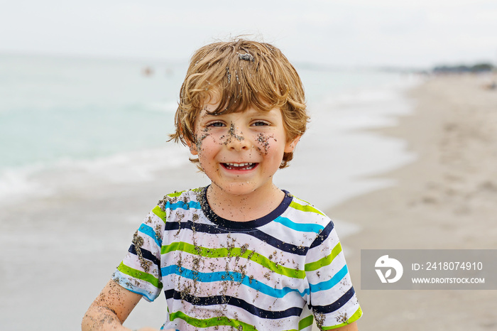 Little kid boy having fun on tropical beach