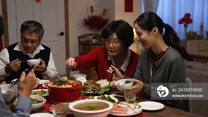 happy asian grandmother and daughter in law giving food to each other while eating dinner together o