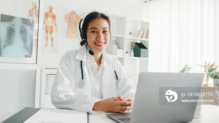 Young Asia lady doctor in white medical uniform with stethoscope using computer laptop talking video