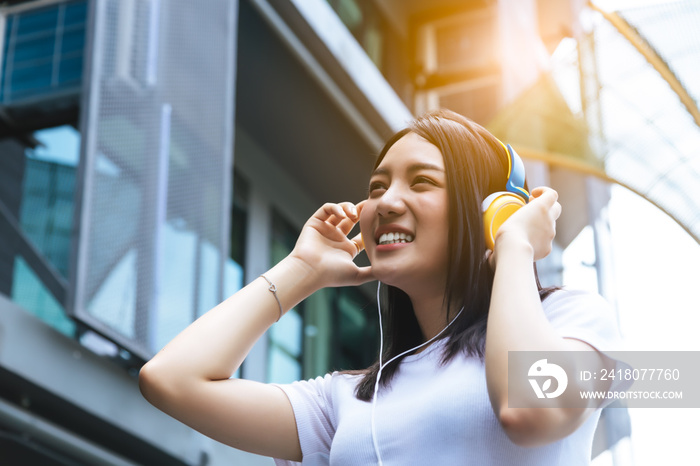 Young woman using headphone for listening nice music in city with building background with toothy sm