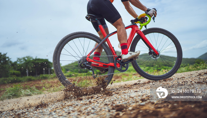 Asian man bicycling on gravel road. He brakes the wheels, causing the soil to spread.