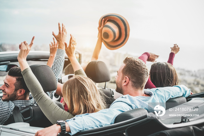 Happy friends with hands up having fun in convertible car on summer vacation