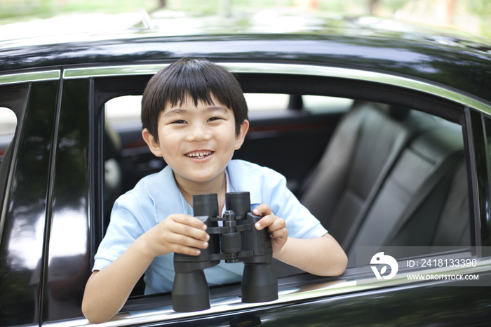 小男孩拿着望远镜看车窗外