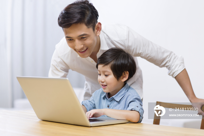 父亲教导男孩用笔记本电脑上网