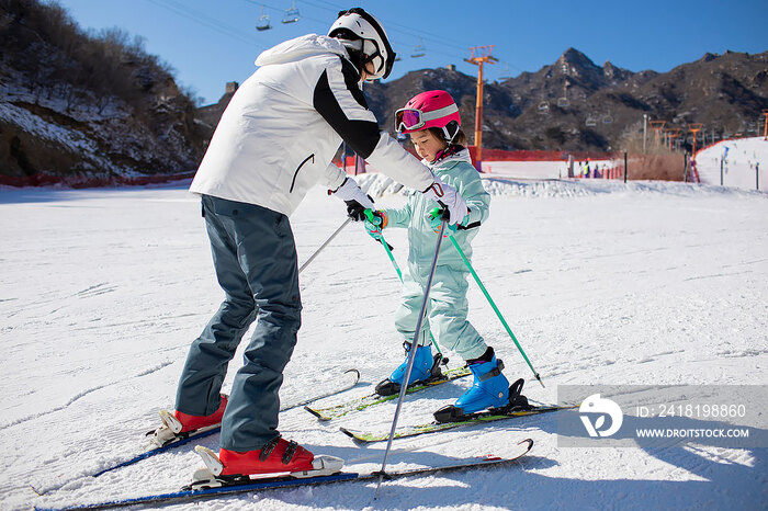 小女孩跟着教练在户外学滑雪