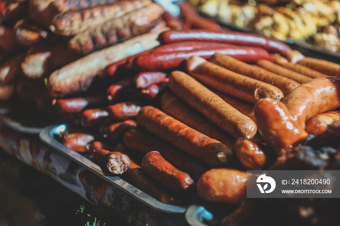 Fried meat sausages on a black background of charcoal.