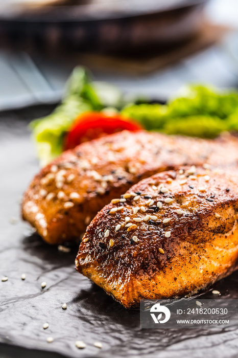 Delicious grilled roasted salmon fillets or steaks with sesame tomatoes and lettuce salad.