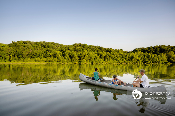 Air Force service member takes his sons canoeing at sunset out on the lake.