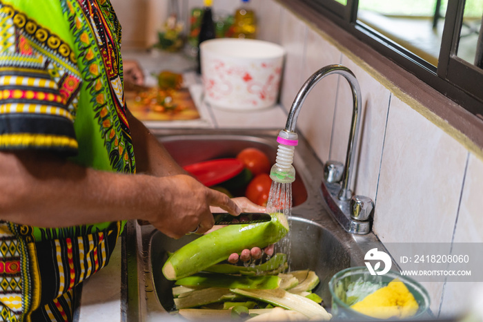 Imagen horizontal de un hombre irreconocible en el interior de su cocina pelando unos plátanos verde