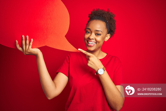 Young african american woman holding speech bubble over red isolated background very happy pointing 