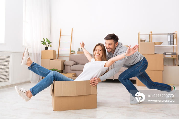 Smiling young couple having fun and riding in boxes