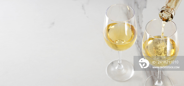 大理石桌子上放着两个装满白葡萄酒的酒杯。倒着甜白葡萄酒。空位