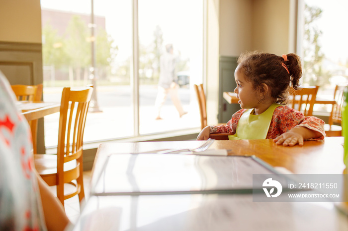 Girl (2-3) sitting at table in restaurant