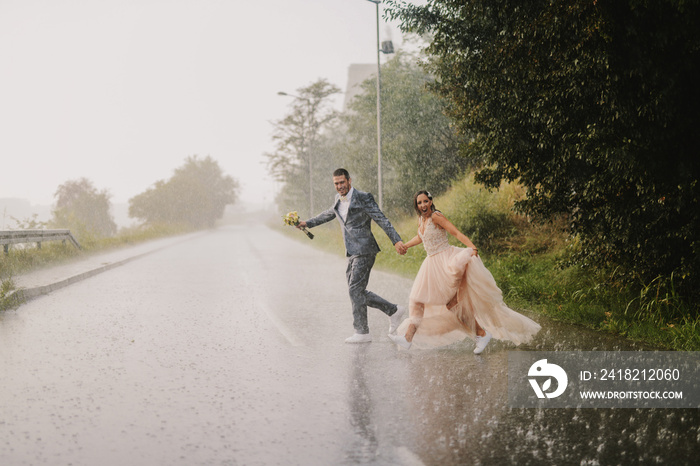 愚蠢的年轻新婚夫妇在雨天过马路。穿着湿衣服跑步。